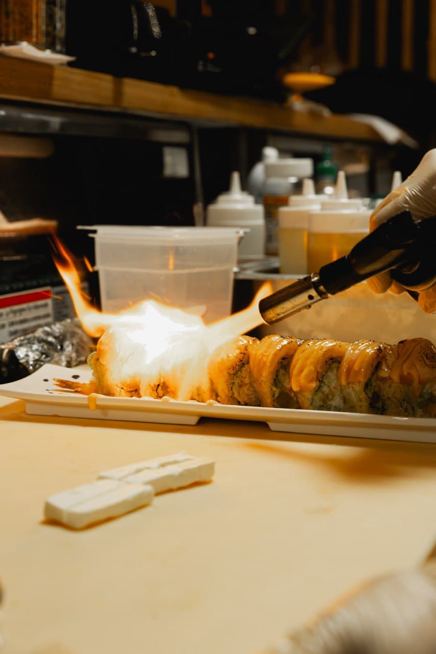 Chef actively torching specialty roll with flame