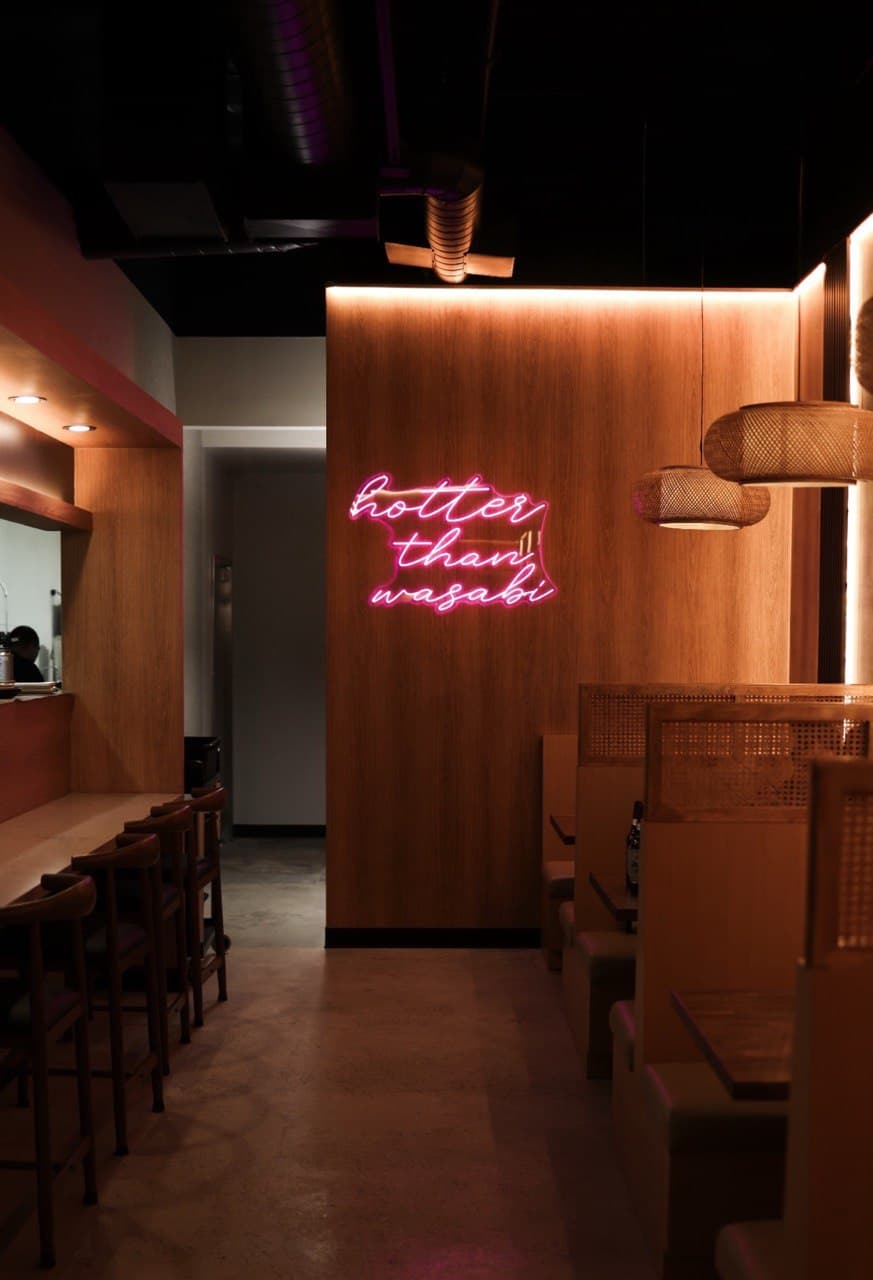 Sushi Club dining room with wood paneling and a pink neon sign